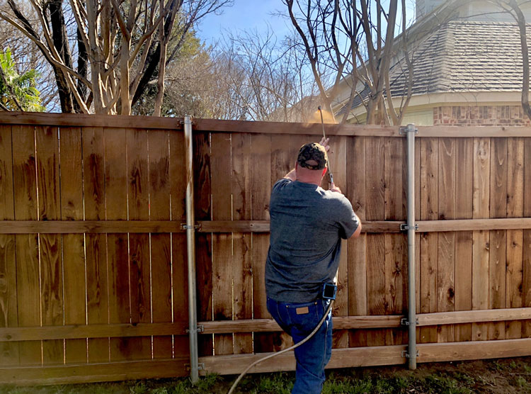 man powerwashing fence